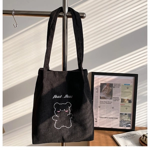 Dettaglio della borsa tote in velluto a coste nero con orsetto ricamato bianco e scritta