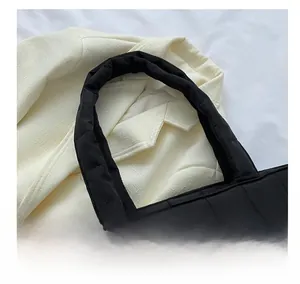 Detail of wide padded handles on a black quilted tote bag with soft fabric texture