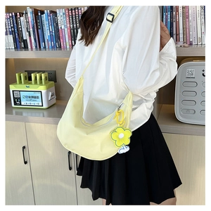 Détail du sac bandoulière croissant jaune clair avec texture nylon et breloque tournesol