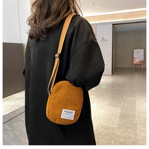 Detailed view of yellow corduroy crossbody bag with adjustable strap and fashion label