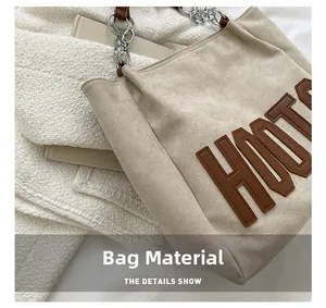 Détail du sac cabas beige avec écusson HOOT et bandoulière en chaîne métallique