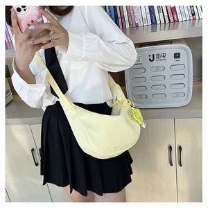 Détail du sac bandoulière croissant jaune clair avec sangle noire et breloque fleur