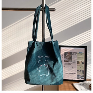 Dettaglio della borsa tote in velluto a coste verde scuro con ricamo di orsetto