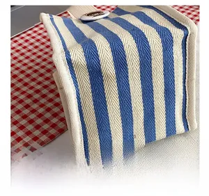 Detail showing the herringbone weave texture and metal buckle of the striped canvas bag