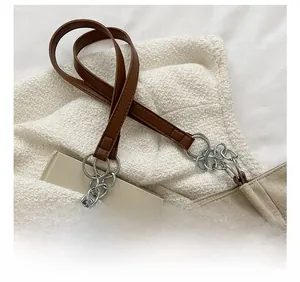 Détail de la bandoulière en cuir marron avec anneaux argentés sur un grand sac fourre-tout