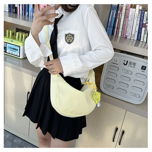 Détail du sac bandoulière croissant jaune clair en toile avec pendentif fleur jaune
