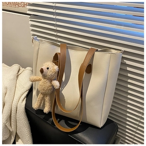 Detail of off-white tote bag with brown leather straps and cute plush bear charm