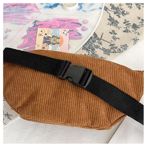 Detail view of brown corduroy waist bag with black nylon strap and buckle closure