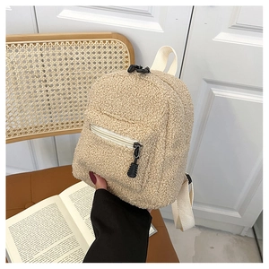 Detail of beige faux shearling mini backpack with black zipper pocket and soft teddy texture