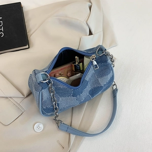 Vintage denim baguette bag with chain strap shown with essentials inside on a blazer