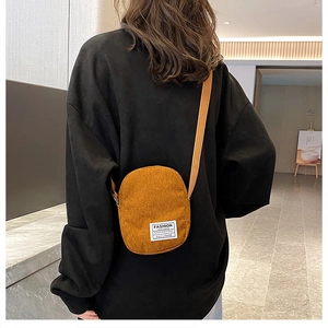 Brown corduroy mini crossbody bag worn by model, featuring fashion label and sleek design