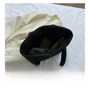 Interior view of black quilted tote bag showing storage for phone, wallet and umbrella