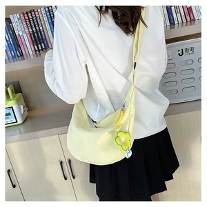Détail d'un sac en toile croissant jaune clair avec un charme de fleur de soleil