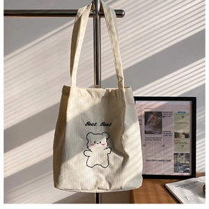 Dettaglio della borsa tote in velluto a coste crema con ricamo a orsetto e texture morbida