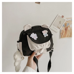 Close-up of black and white cartoon bunny crossbody bag with a cute plush bear pendant