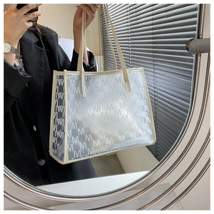 Detail view of semi-transparent PU tote bag with large M-letter pattern and shoulder straps