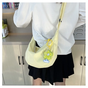 Vue détaillée du sac bandoulière demi-lune en toile jaune avec breloque fleur en peluche