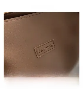 Close-up of deep brown leather tote bag detail with embossed Fashion logo and neat stitching