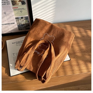 Dettaglio borsa tote in velluto a coste marrone con ricamo di orso e texture a righe