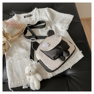 Detail of panda themed crossbody bag with cute ears, badges and plush bear charm
