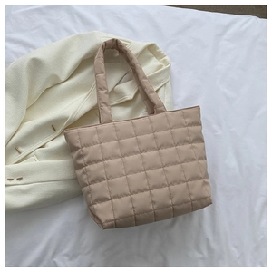 Close-up of beige quilted nylon tote bag showing square stitching texture and long handles