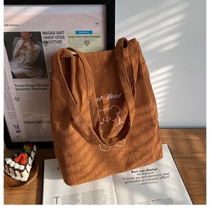 Dettaglio borsa tote in velluto marrone con orsetto ricamato e scritta Beat