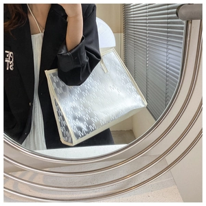 Detail of white PU tote bag with M-letter pattern and elegant mirror reflection shot