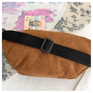 Close-up of brown corduroy chest bag with thick ribbed texture and black nylon strap