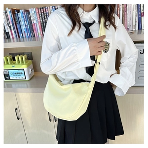 Détail d'un sac bandoulière en demi-lune jaune clair porté par un mannequin en intérieur