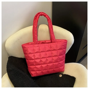 Detailed view of magenta quilted nylon tote bag with puffer texture on a chair