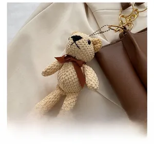 Close-up of a cute beige knitted bear charm with a brown bow on a tote bag