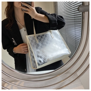 Detail of transparent tote bag with white M-pattern and cream leather trim