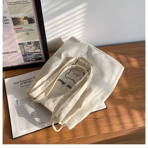Dettaglio della borsa tote in velluto a coste bianco crema con orsetto e trama a costine