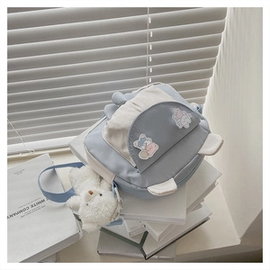Close-up of blue and white canvas bag with rabbit ears and plush bear charm