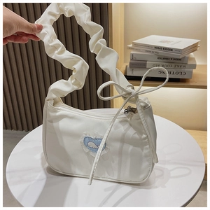 Detail der weißen Plissee-Tasche mit blauem Herz-Wal-Patch und eleganter Spitzenkante