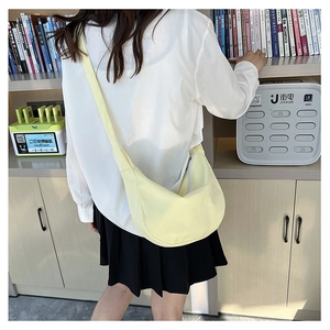 Détail d'un sac bandoulière demi-lune jaune clair avec large sangle sur mannequin
