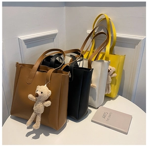 Detail of minimalist tote bags in brown, black and white with cute teddy bear pendants
