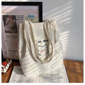 Dettaglio della borsa tote in velluto a coste bianco con ricamo orsetto sulla scrivania
