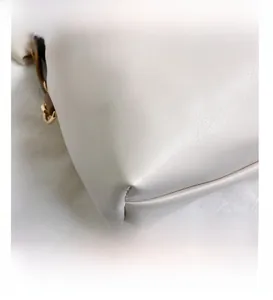 Dettaglio della borsa in pelle bianca con cuciture rinforzate e fibbia in metallo dorato