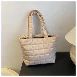 Detail of champagne gold quilted tote bag showing puffer nylon texture and stitching