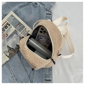 Capacity detail of mini beige faux shearling backpack holding a phone and bottle