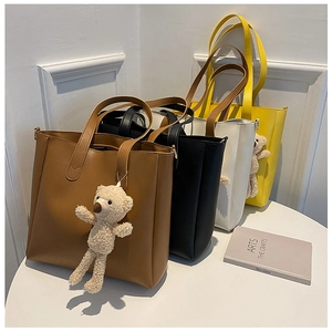 Close-up of matte leather tote bags in four colors featuring cute plush bear charms