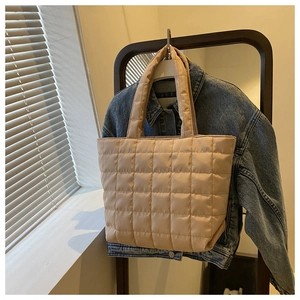 Detail of apricot quilted tote bag with square stitching hung over a denim jacket