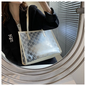 Close-up of a transparent PVC tote bag with M-letter print and beige leather edges