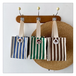 Three striped canvas lunch bags in blue, green, and brown with cute cartoon badges