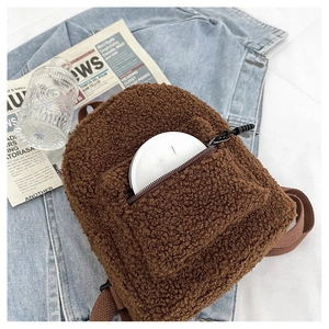 Close-up of brown faux shearling mini backpack with front zipper pocket on denim