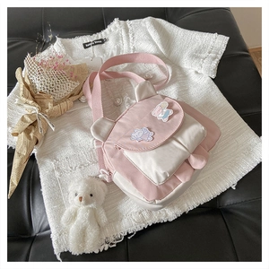 Detail of pink and white canvas crossbody bag with cute bear ears and plush charm