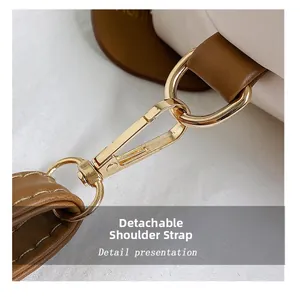 Dettaglio della tracolla staccabile in pelle marrone con fibbia dorata su borsa bianca