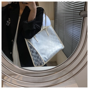 Detail view of large grey tote bag with white letter pattern and cream leather trim