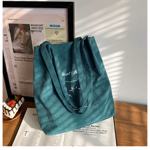 Dettaglio borsa tote in velluto a coste con ricamo di orsetto e scritta in bianco